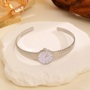 Detail of creative silver watch ring with white dial on textured stone