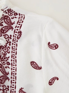 Nahaufnahme von weißem Stoff mit dunkelrotem Paisleymuster zeigt Textur und Details