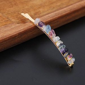 Macro detail of multicolored natural crystal stone chips on a golden metal hair clip