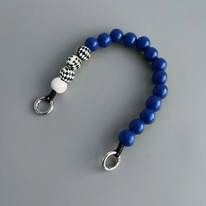 Detail of blue and checkerboard wooden beads on mobile phone strap with metal clasp