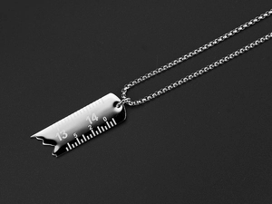Détail macro du pendentif règle cassée en argent montrant les numéros gravés