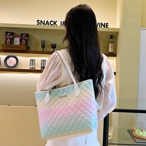 Quilted gradient tote bag in pastel colors shown on shoulder in a cozy cafe setting