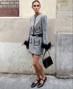Detail of grey tweed jacket featuring elegant black feather cuffs and gold buttons
