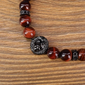 Detailopname van een 8mm rode tijgeroog armband met een leeuwenkop en zwarte afstandhouders