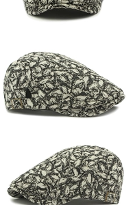 Close-up of vintage newsboy cap with black leaf jacquard pattern and bronze buckle