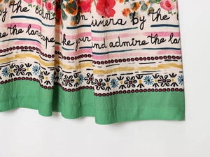 Close-up of floral chiffon fabric with cursive text and green stripe border detail