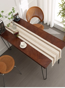 Detailed close-up of woven cotton linen table runner with geometric patterns and tassels