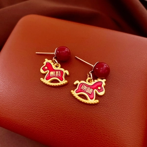 Macro shot of red enamel rocking horse earrings with golden finish and lucky engraving