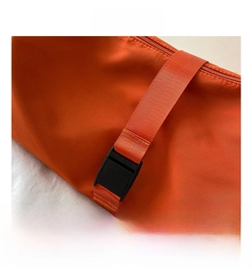 Detail shot of sturdy plastic buckle and nylon strap on an orange Oxford crossbody bag