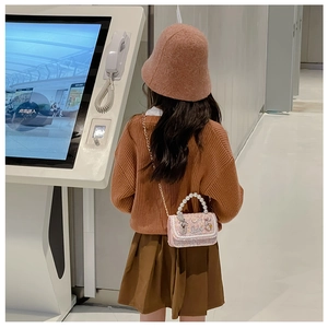 Pink sequin girls crossbody bag with pearl handle and gold chain on model's back