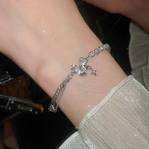 Close-up of sparkling zircon butterfly and star charms on a dual-layer silver chain bracelet