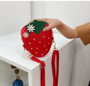 Detail of red strawberry shaped crossbody bag with gold studs and daisy floral accents