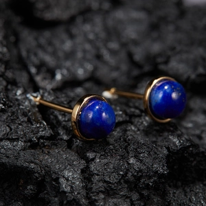 Macro shot of gold-plated S925 silver stud earrings with natural lapis lazuli on stone