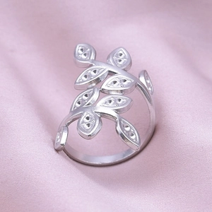 Detailed view of silver leaf pattern ring on pink satin fabric showing texture
