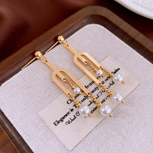 Détails des boucles d'oreilles dorées géométriques avec perles blanches sur bois