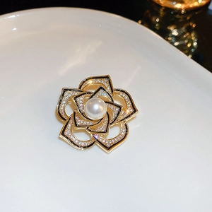 Détail de la broche camélia dorée avec zircons brillants, émail noir et une perle centrale