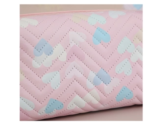 Close-up of pink quilted PVC makeup bag featuring blue and white heart print patterns