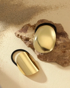 Detail of high-elastic black hair ties with decorative oval gold metal accents on stone