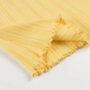 Gros plan sur le tissu en maille côtelée jaune avec bords délicats en finition ondulée