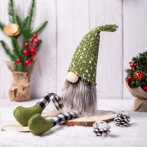 Detail of Christmas gnome with green knit hat and plaid legs on rustic wooden base