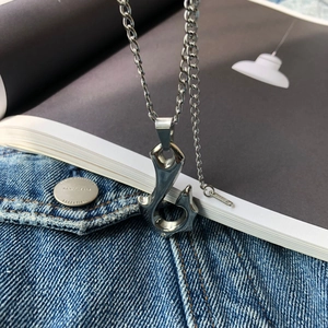 Silver fish hook pendant necklace with sparkling diamonds on a denim jacket background