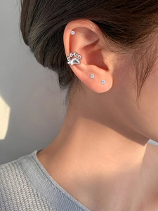Close-up of cute cat paw ear cuff in polished silver metal on female model ear