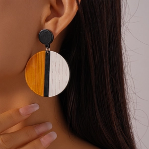 Detail of geometric acrylic round earrings featuring yellow, black, and white wood texture