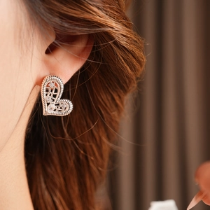 Close-up of silver-plated heart earrings with zircon inlay worn by a model
