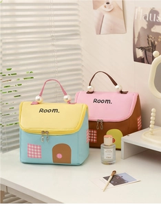 Dettagli di pochette trucchi a forma di casa con manici di perle e motivi a griglia