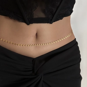 Detailed view of an 18k gold-plated sun flower waist chain worn over a black lace dress