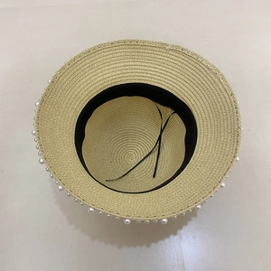 Detailed view of women's straw sun hat interior with pearl trim and adjustable strap