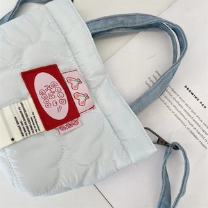 Détail du mini sac matelassé bleu clair avec patch rouge et bandoulière en denim
