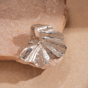 Macro detail of silver wavy fan-shaped metal ring with a polished mirror finish surface
