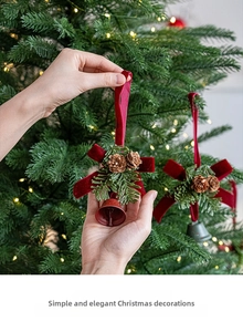 Nahaufnahme eines Weihnachtsglocken-Anhängers mit Samtschleife, Tannenzapfen und Nadeln