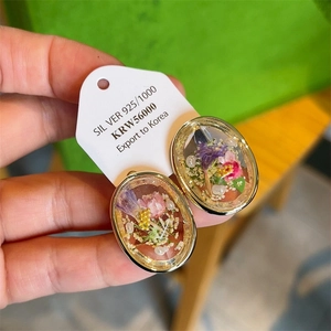 Macro shot of 18K gold plated amber earrings with real dried flowers and 925 silver tag