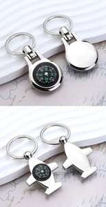 Detail of silver metal compass keychains in round and airplane shapes on map background