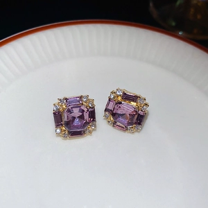 Macro view of vintage gold square stud earrings with purple crystals and white diamonds