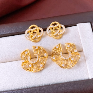 Detail view of gold earrings with cubic zirconia inlay and hollow mesh design in jewelry box
