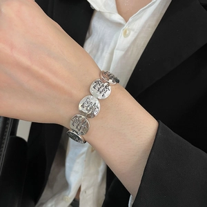 Close-up of silver metal discs bracelet with engraved inspirational text on model