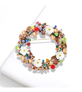 Dettaglio di spilla floreale oro antico con strass colorati, fiori di conchiglia e perle