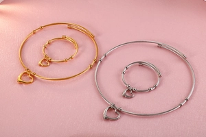 Detailed view of heart charms on gold and silver wire cable choker necklaces and bracelets