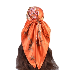 Dettaglio di un foulard quadrato in raso con base arancione e motivi di fiori di prugno rosa