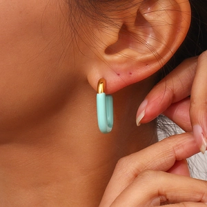 Close-up of U-shaped gold-plated earring with mint green enamel on woman ear