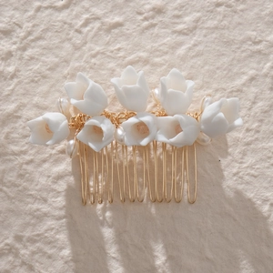 Close-up of white ceramic floral bridal hair comb with elegant gold metal teeth