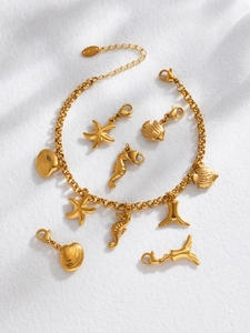 Détail d'un bracelet océan doré avec des breloques hippocampe, étoile de mer et coquillage