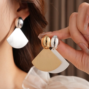 Close-up of matte brushed fan-shaped earrings with oval studs in gold and silver finish