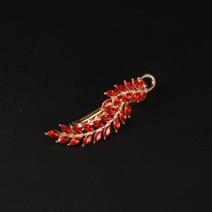 Macro shot of gold leaf hairpin with red marquise-cut crystals on a black background