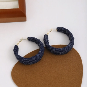 Close-up of blue denim hoop earrings with white polka dots and gold-plated metal hooks