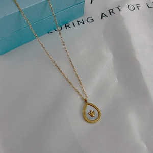 Macro shot of gold teardrop pendant with white mother of pearl and crown detail