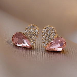 Macro shot of pink heart stud earrings with gold plating and sparkling crystal pave details